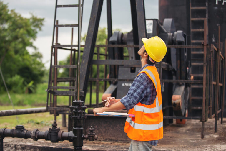 Workers standing and checking beside working oil pumps